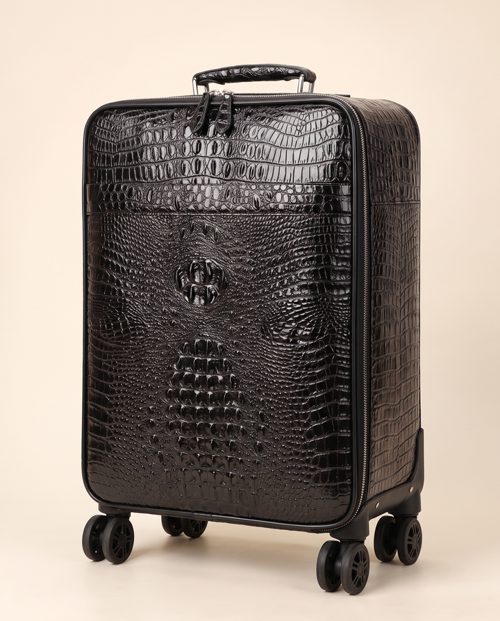 The Zermatt 58 crocodile trolley case in black, three-quarter view on a cream studio backdrop